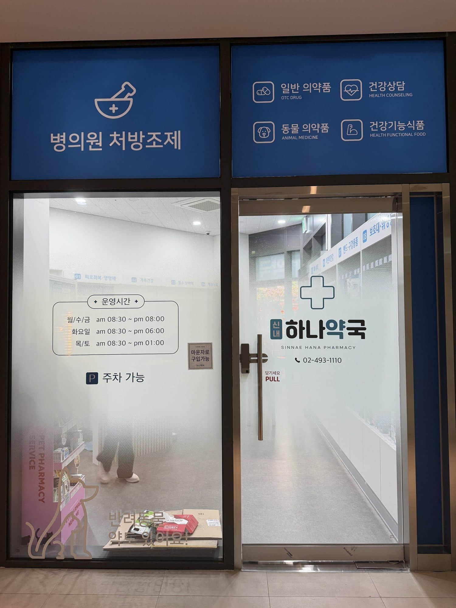 약국 출입구 유리문에 붙은 영업시간 안내와 로고
