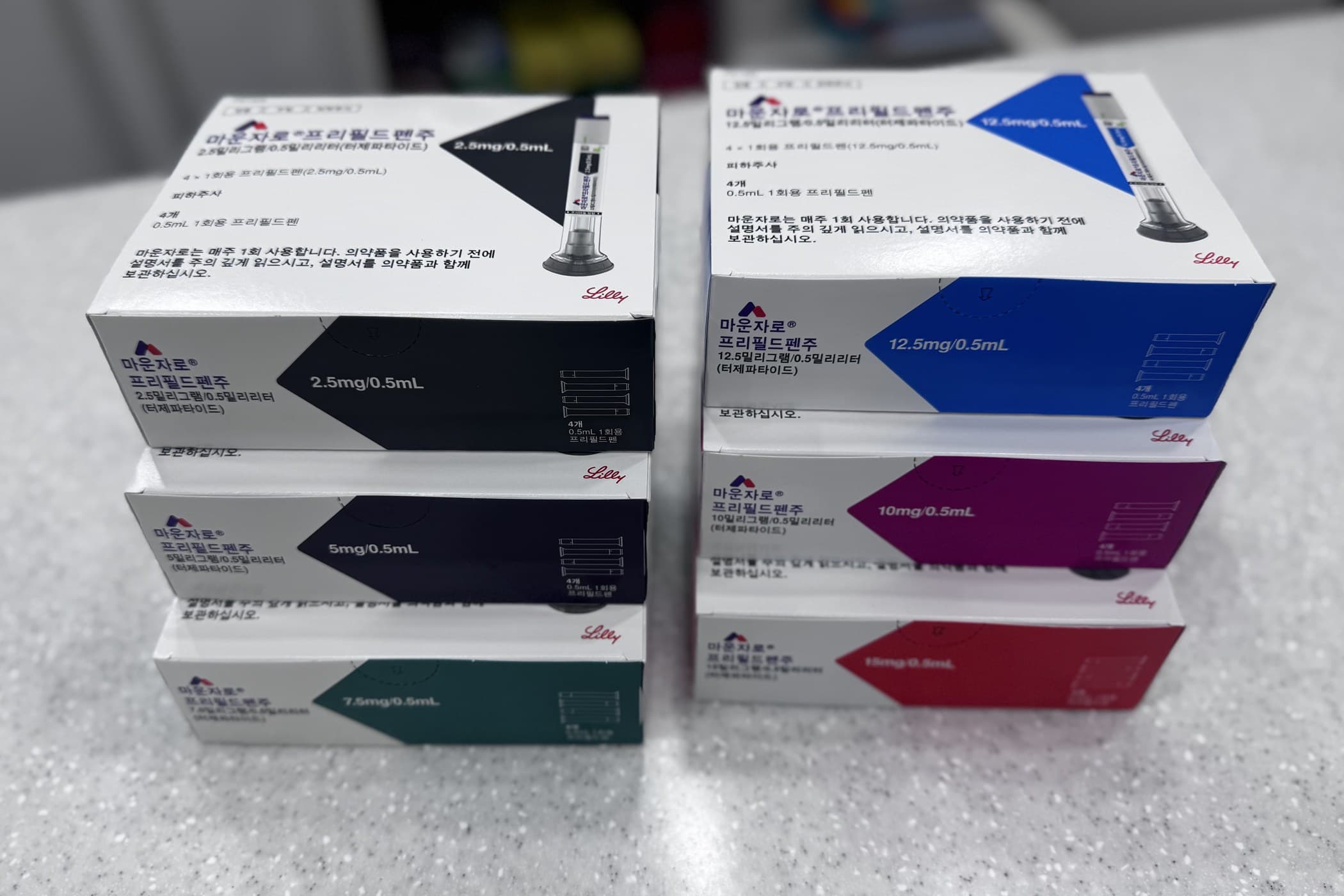 마운자로 프리필드펜 용량별 상자 여섯 종(2.5mg~15mg)이 약국 카운터에 놓여 있다